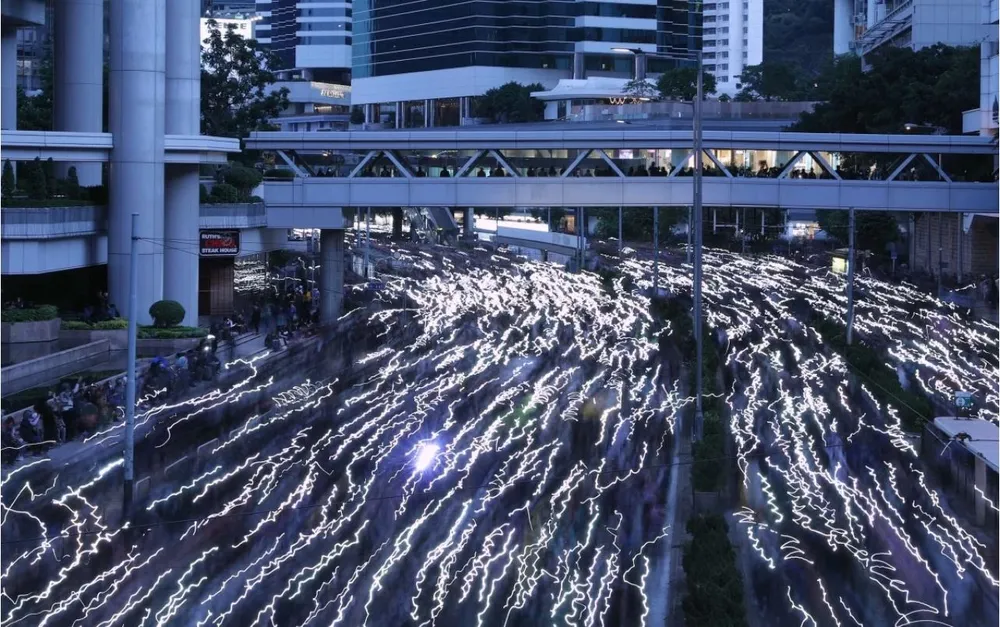 Người biểu tình dùng đèn điện thoại tạo dòng ánh sáng trên đường phố, tối 8-12. Ảnh: SCMP