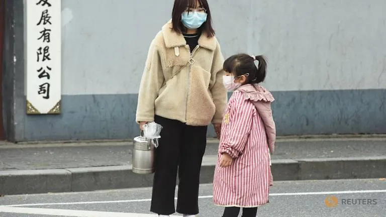 Mẹ con mang khẩu trang trên đường phố Hàng Châu, tỉnh Chiết Giang (Trung Quốc) ngày 21-1. Ảnh: REUTERS