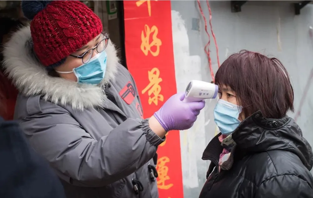 Kiểm tra nhiệt độ cơ thể người dân trên đường phố Vũ Hán, tỉnh Hồ Bắc (Trung Quốc) ngày 7-2. Ảnh: THX