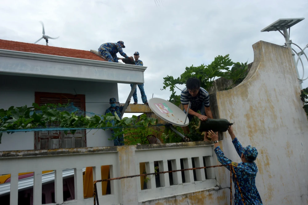 Cán bộ, chiến sĩ đảo Sinh Tồn giúp nhân dân chằng buộc mái nhà. Ảnh: NGUYỄN TOÀN.