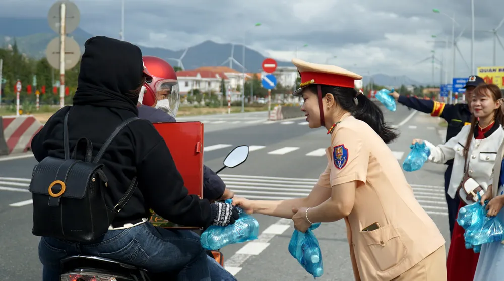 CSGT Ninh Thuận hỗ trợ nước cho người dân đi xa máy về quê. Ảnh: HH