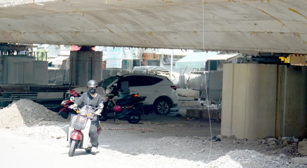 Một số người liều mình đi dưới gầm cầu để lưu thông từ huyện Diên Khánh về TP Nha Trang thay vì phải lên cầu Nút giao Ngọc Hội ra đường vành đai 2. Trên đầu là những máy cơ giới ầm ầm thi công.