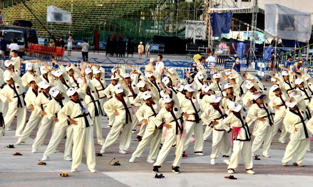 370 cụ trong trang phục màu vàng Thái cực trường sinh đạo xếp đội hình đồng diễn bốn bài thể dục dưỡng sinh với chủ đề &quot;Khỏe vì nước&quot; với những bước đi uyển chuyển và những động tác thái cực trường sinh đạo theo tiếng nhạc.