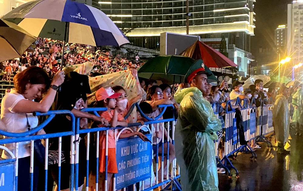 Người dân và du khách mang áo mưa, che dù xem chương trình bế mạc. Ảnh: CHU VÂN