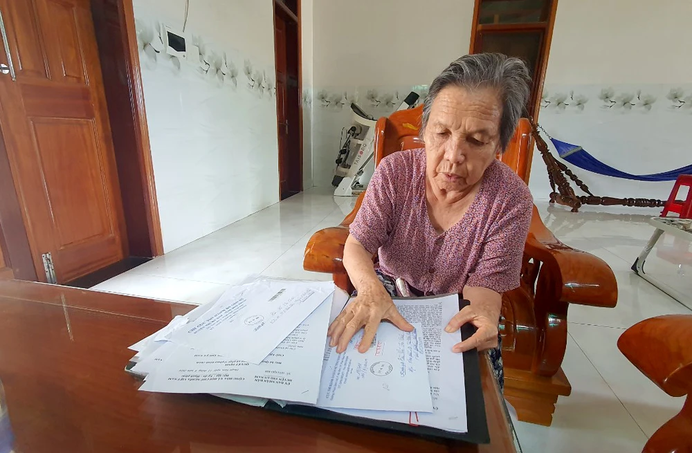 Bà Võ Thị Quê cùng hồ sơ khiếu nại hơn 10 năm qua. Ảnh: H.H thi hành án.jpg