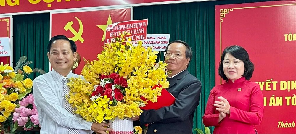 Phó Chánh án TAND TP.HCM Phạm Thị Thu Hà và lãnh đạo địa phương trao quyết định bổ nhiệm và tặng hoa chúc mừng Tân Chánh án TAND huyện Bình Chánh Vũ Thanh Lâm. Ảnh: HOÀNG YẾN
