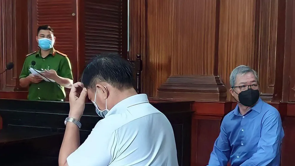 Bị cáo Cường (áo xanh) quay tìm người thân khi HĐXX hội ý. Ảnh: H.YẾN