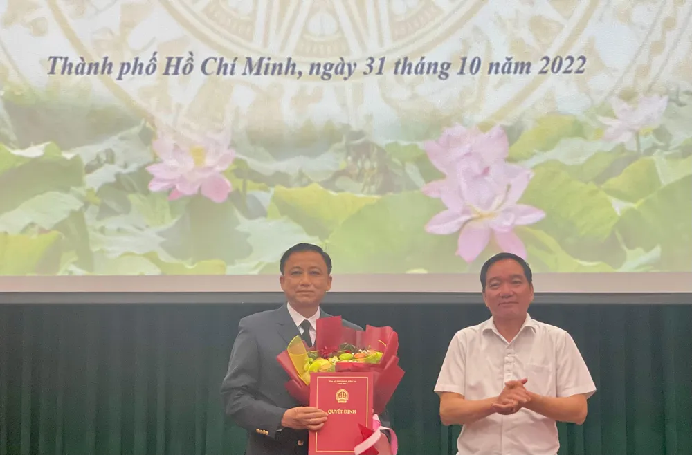 Ông Trần Anh Tuấn - Vụ trưởng Vụ tổ chức cán bộ TAND Tối cao trao quyết định và tặng hoa cho tân phó chánh án TAND Cấp cao tại TP.HCM. Ảnh: HOÀNG YẾN