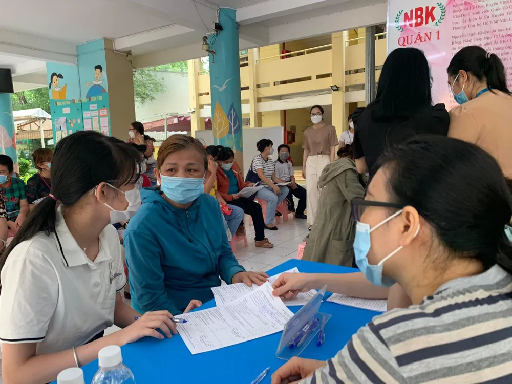 Chị Giàu và con gái đang điền thông tin vào phiếu đồng thuận tiêm chủng. Ảnh: HOÀNG LAN