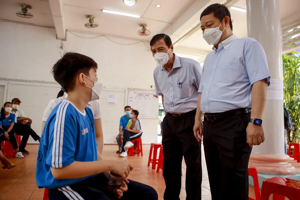 Phó Chủ tịch TP Dương Anh Đức hỏi thăm một em học sinh sau khi tiêm chủng. Ảnh: NGUYỆT NHI