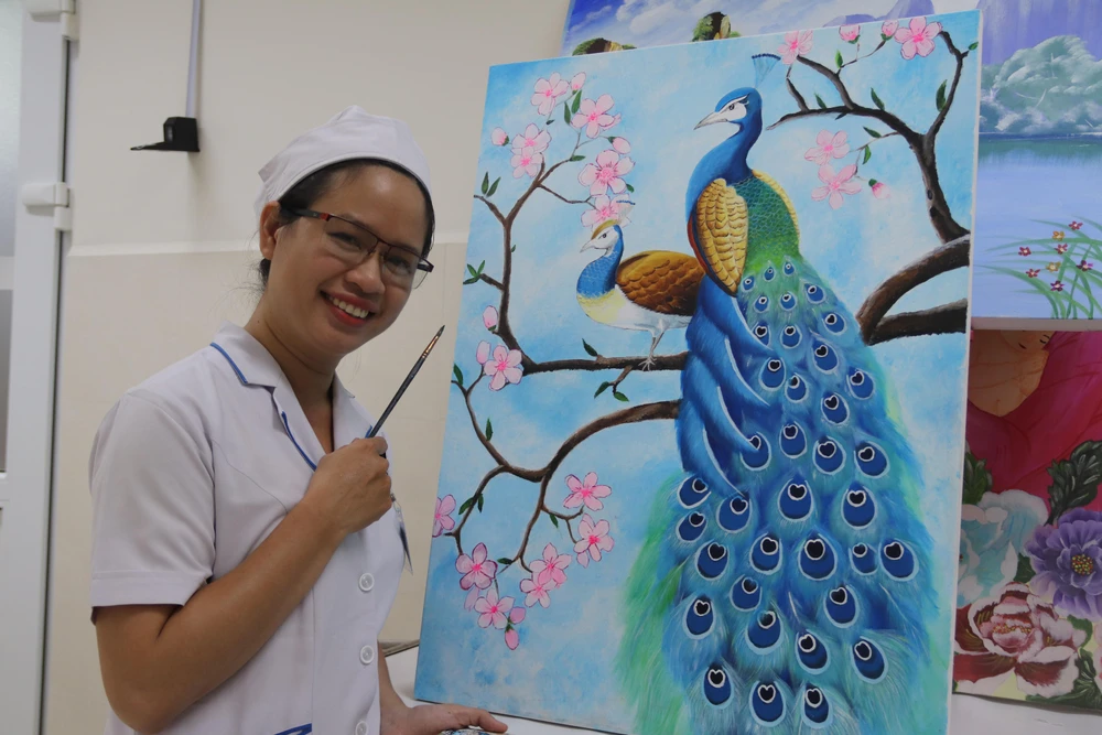 Nữ hộ sinh Nguyễn Thị Thúy An bên bức vẽ của mình. Ảnh: HOÀNG LAN