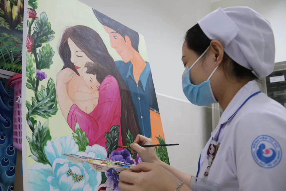 Nữ hộ sinh Trần Thị Thùy Trang và tác phẩm của mình. Ảnh: HOÀNG LAN