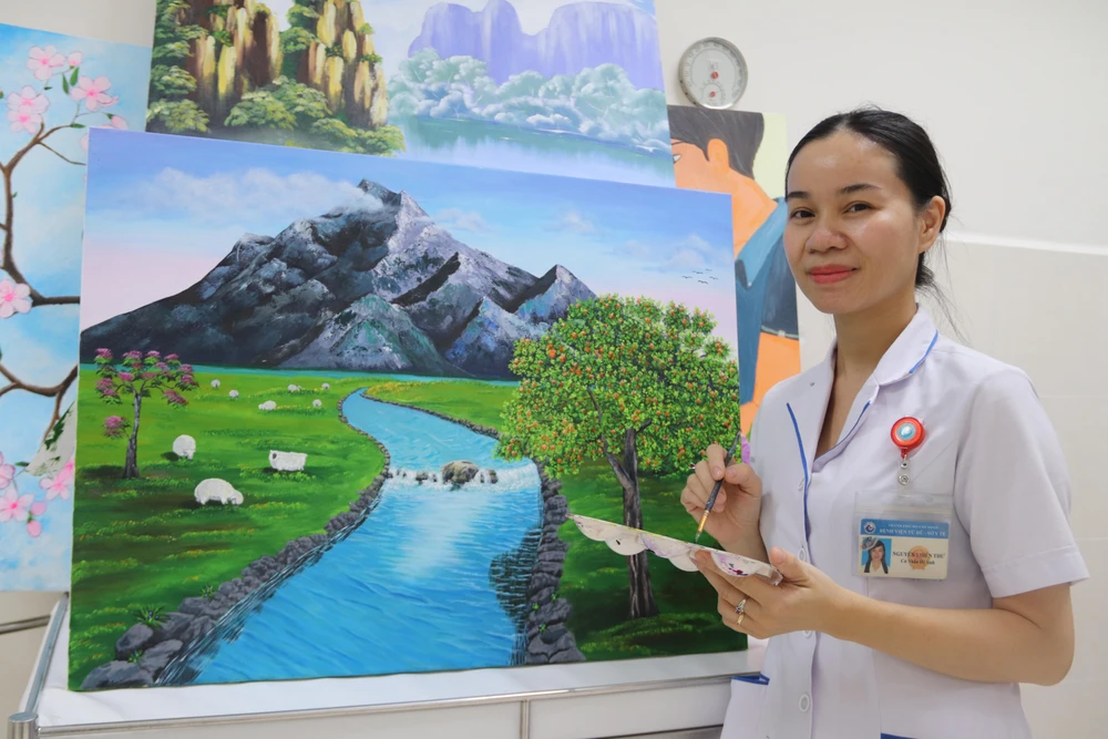 Nữ hộ sinh Nguyễn Thiên Thư bên bức vẽ của mình. Ảnh: HOÀNG LAN
