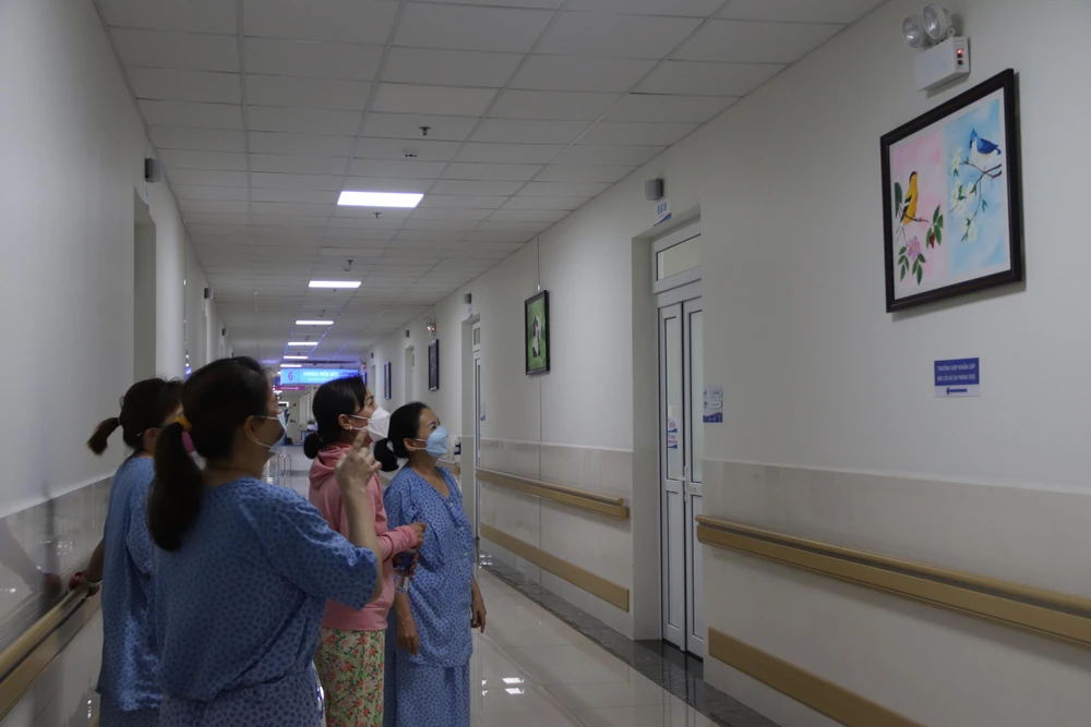 Bệnh nhân chiêm ngưỡng các bức vẽ dọc hành lang. Ảnh: HOÀNG LAN