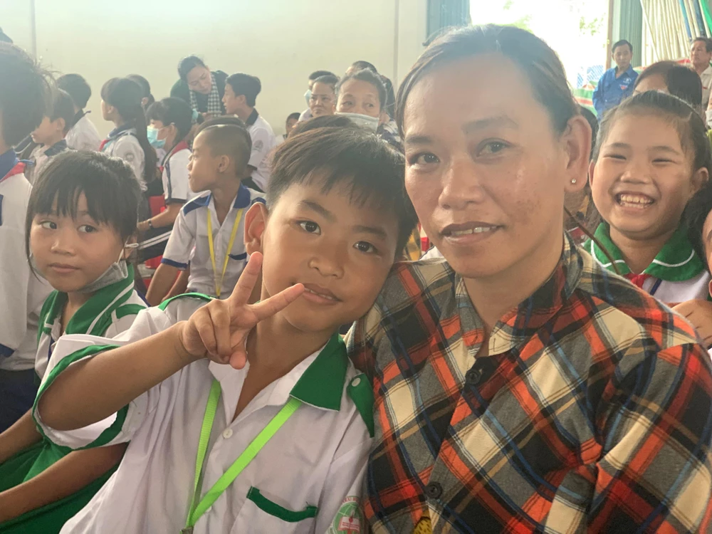 Chị Vũ Thị Linh cùng con hào hứng trước khi nhận quà. Ảnh: H.LAN