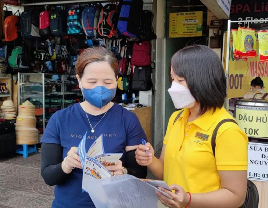 Tiểu thương chợ Bến Thành (quận 1, TP.HCM) được tư vấn quyền lợi khi tham gia BHXH tự nguyện. Ảnh: NGUYỄN HIỀN