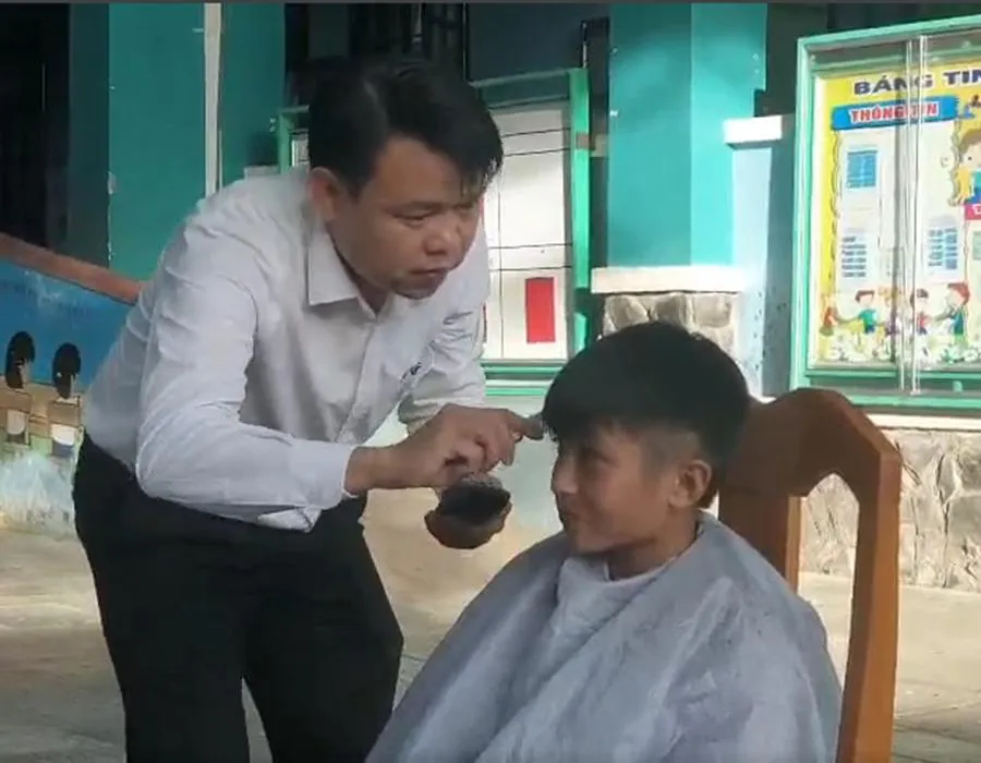 Thầy Lê Hữu Bình, Hiệu trưởng nhà trường, đang hớt tóc cho học trò. Ảnh: NGUYỄN QUYÊN