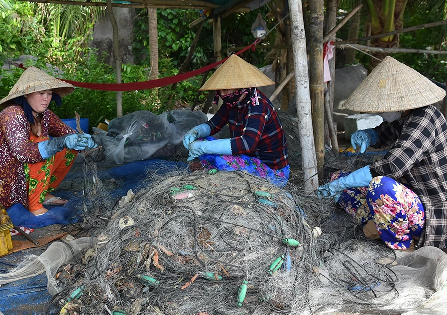 Phụ nữ làng chài Trần Phú, TP Phú Quốc vá lưới chuẩn bị cho chuyến ra khơi mới của chồng. Ảnh: MINH TRUNG