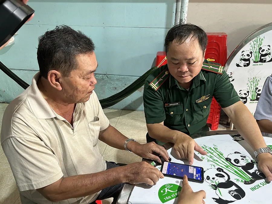 Ngư dân Phan Thanh Bình (trái) đang trình bày về việc theo dõi giám sát hành trình tàu cá qua app trên điện thoại. Ảnh: HỒNG NHUNG Bo sung hinh_P2-3_IUU_bai chinh_3h_Anh_Man.jpg
