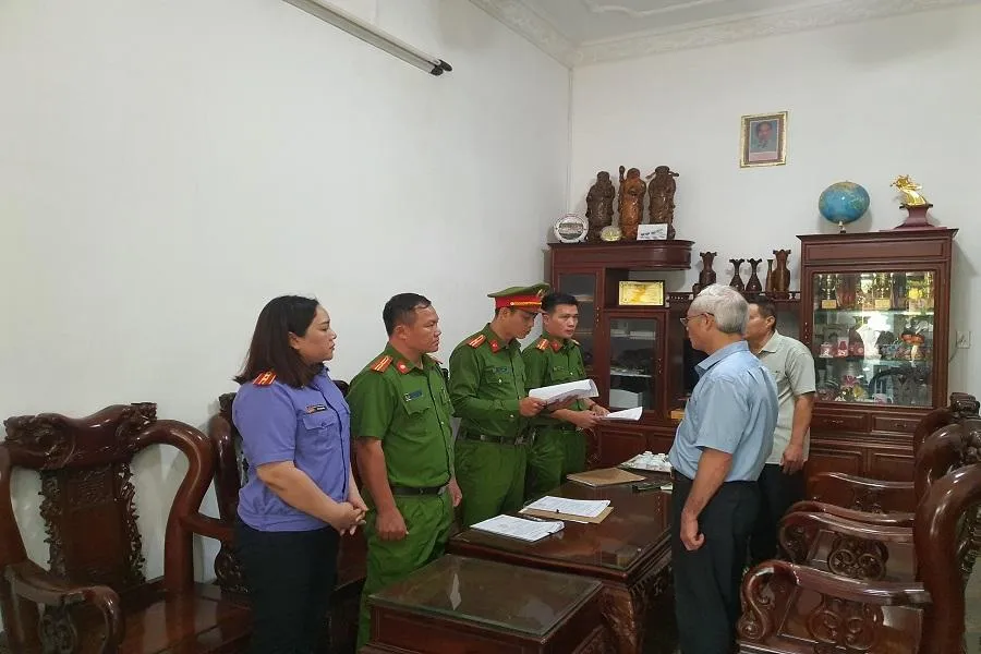 Công an đang đọc quyết định khởi tố bị can. Ảnh AL