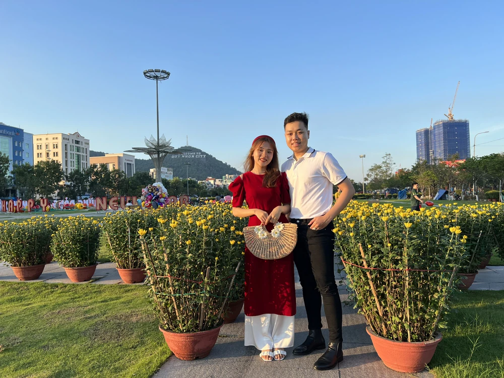 Đôi bạn trẻ chụp ảnh tại các gian hàng hoa Tết. Ảnh QN