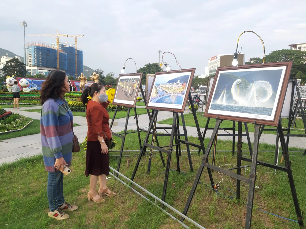 Nhiều người tranh thủ chiêm ngưỡng những bức tranh đẹp được trưng bày tại quảng trường Quy Nhơn. Ảnh QN