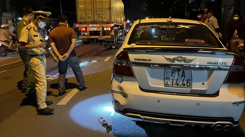 Hai thanh niên tông vào đuôi ô tô rồi ngã văng ra đường và bị xe container tông trúng. Ảnh: LA