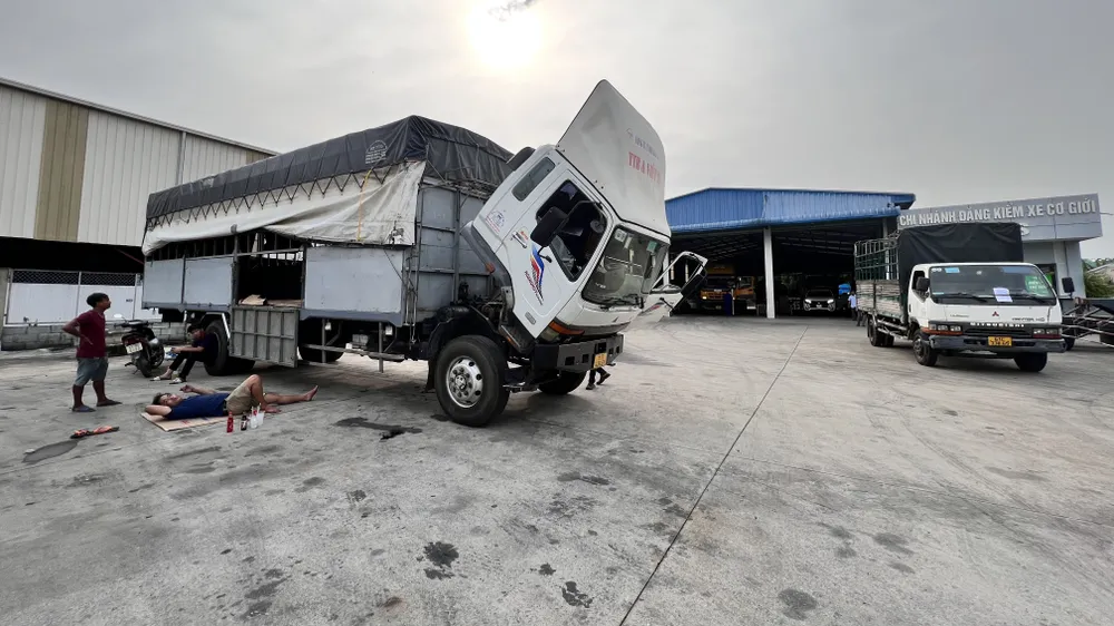Tài xế trải chiếu nằm trong trong sân Trung tâm đăng kiểm xe cơ giới 61-03S. Ảnh: LÊ ÁNH