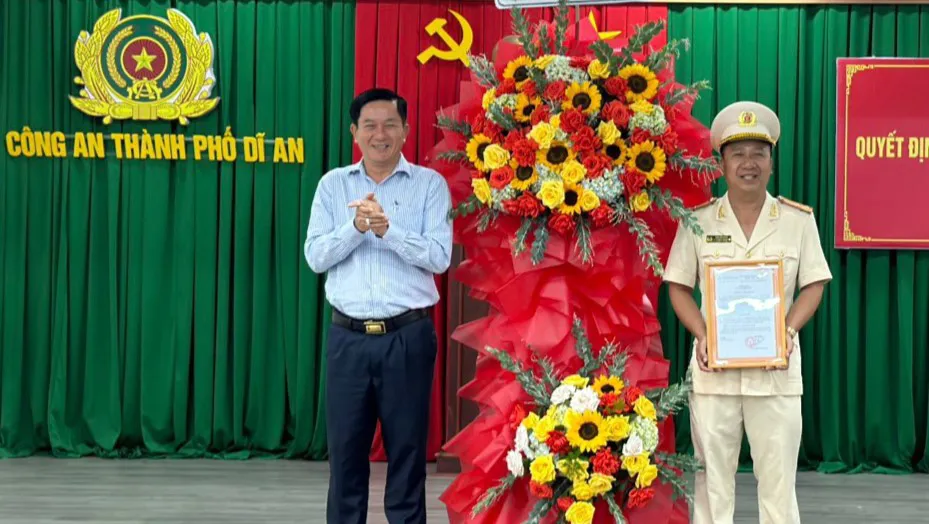 Ông Võ Văn Hồng, Chủ tịch UBND TP Dĩ An (bên trái, nguyên Trưởng Công an TP Dĩ An) tặng hoa chúc mừng cho thượng tá Đàm Bảo Quân. Ảnh: LA