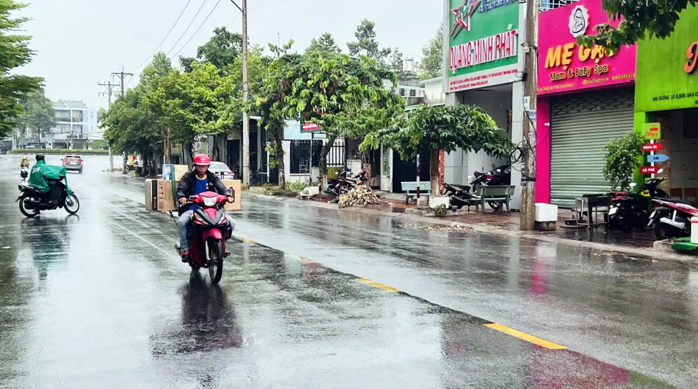 Cơn mưa bất chợt khiến một số người dân không kịp mặc áo mưa. Ảnh: LÊ ÁNH