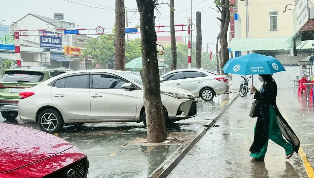 Người dân phải đội mưa đi làm nhưng vẫn thích thú, vì cơn mưa đã làm trời dịu mát. Ảnh: LÊ ÁNH