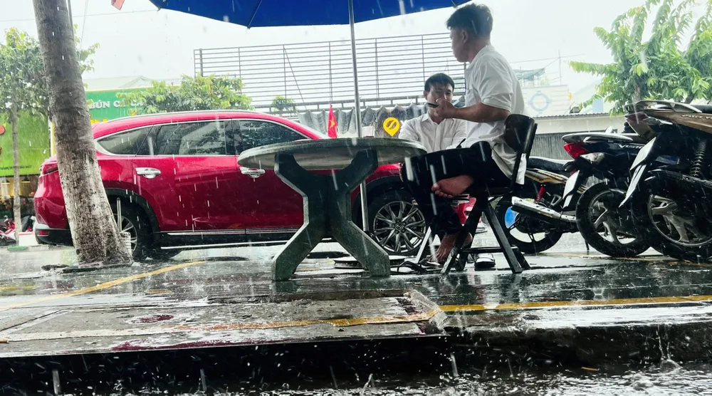 Phấn khích vì trời mưa, người dân ngồi uống cà phê ngoài trời cho đã mát. Ảnh: LÊ ÁNH