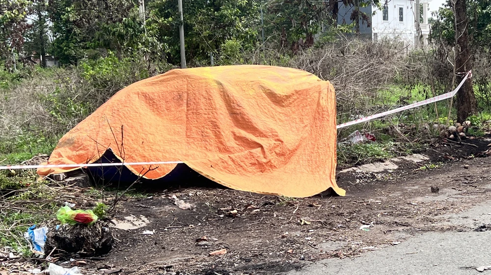 Nơi phát hiện một phần thi thể bị đốt cháy, lực lượng công an che bạt để tránh trời mưa. Ảnh: LÊ ÁNH