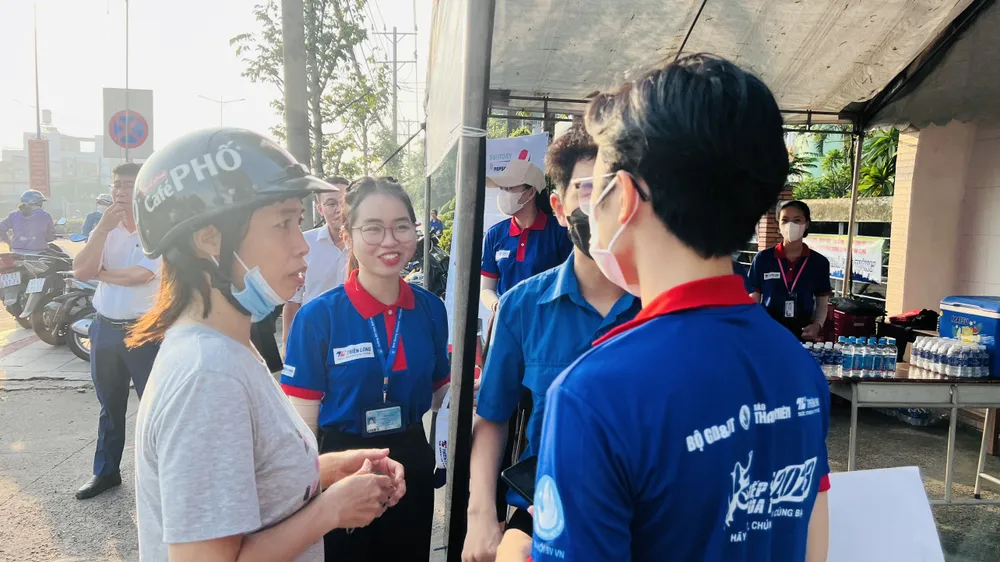 Một phụ huynh nhờ các bạn sinh viên tình nguyện đưa đồng hồ vào cho con. Ảnh: LÊ ÁNH