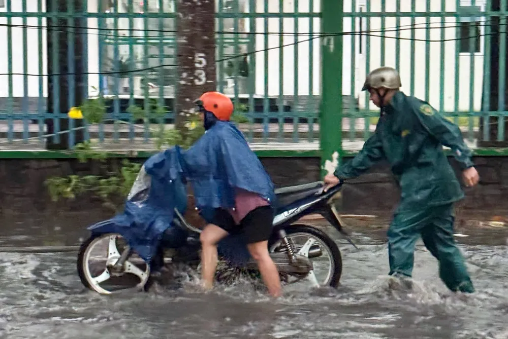 Lực lượng chức năng hỗ trợ người dân đẩy xe qua đoạn đường bị ngập. mưa lớn (2).jpg