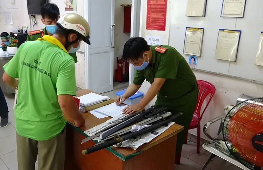 Người dân giao nộp vũ khí tại quận 1 được tặng 10kg gạo. Ảnh: CA giao-nop-vu-khi.jpg