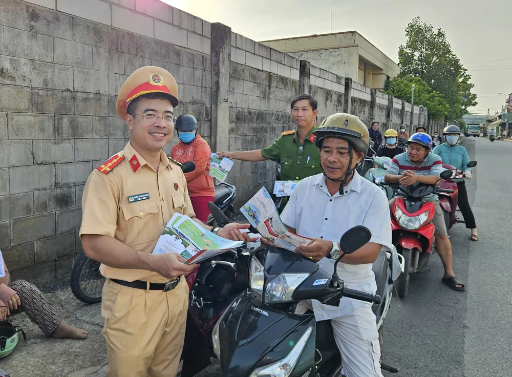 CSGT còn tặng tờ rơi tuyên truyền về an toàn giao thông cho phụ huynh. Ảnh: T.NGHĨA Ttram-csgt-tan-tuc-5.jpg