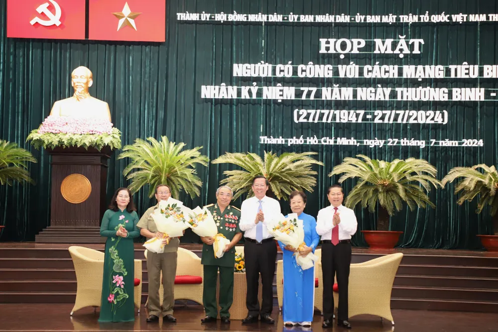 Chủ tịch UBND TP.HCM Phan Văn Mãi và Chủ tịch HĐND TP.HCM Nguyễn Thị Lệ tặng hoa cho các tấm gương tiêu biểu. Ảnh: HÀ THƯ gia-dinh-chinh-sach-6.jpg