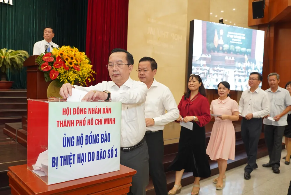 Các đại biểu HĐND TP, khách mời ủng hộ đồng bào bị thiệt hại do bão số 3. Ảnh: THUẬN VĂN bao-so-3-4.jpg