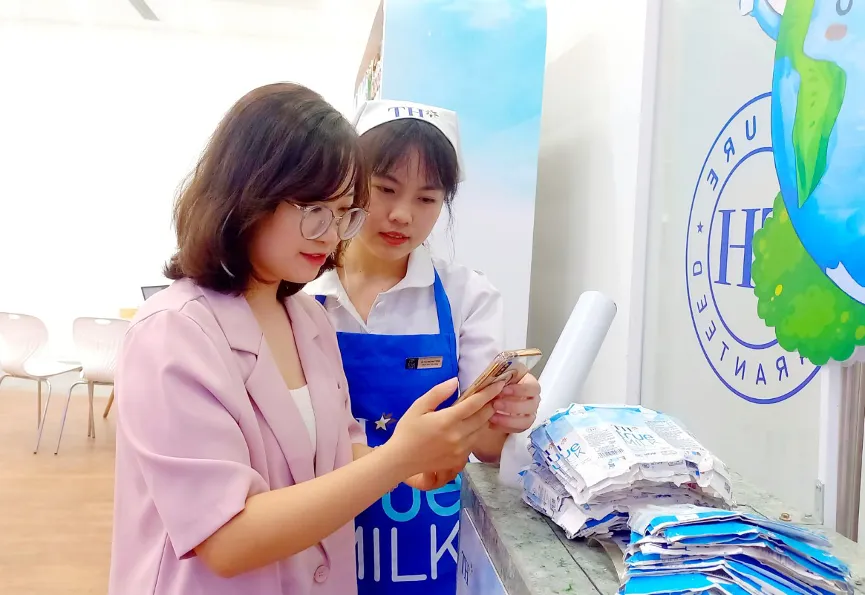 Chị Hiếu Ngân được nhân viên hướng dẫn quét mã quay thưởng khi đến TH true mart tham gia chương trình “Thu gom vỏ hộp, lan tỏa sống xanh 2024”. Người trẻ lan tỏa chương trình “Thu gom vỏ hộp, lan tỏa sống xanh” cùng TH true MILK