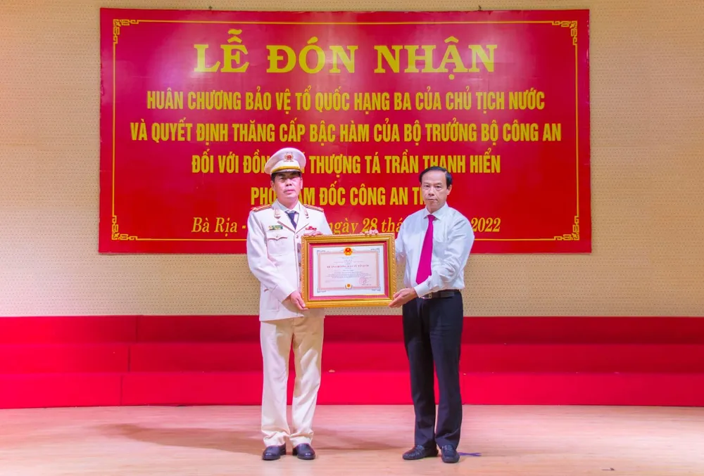 Ông Nguyễn Văn Thọ thừa ủy quyền của Chủ tịch nước trao quyết định cho thượng tá Trần Thanh Hiển. Ảnh: LƯU TRUNG