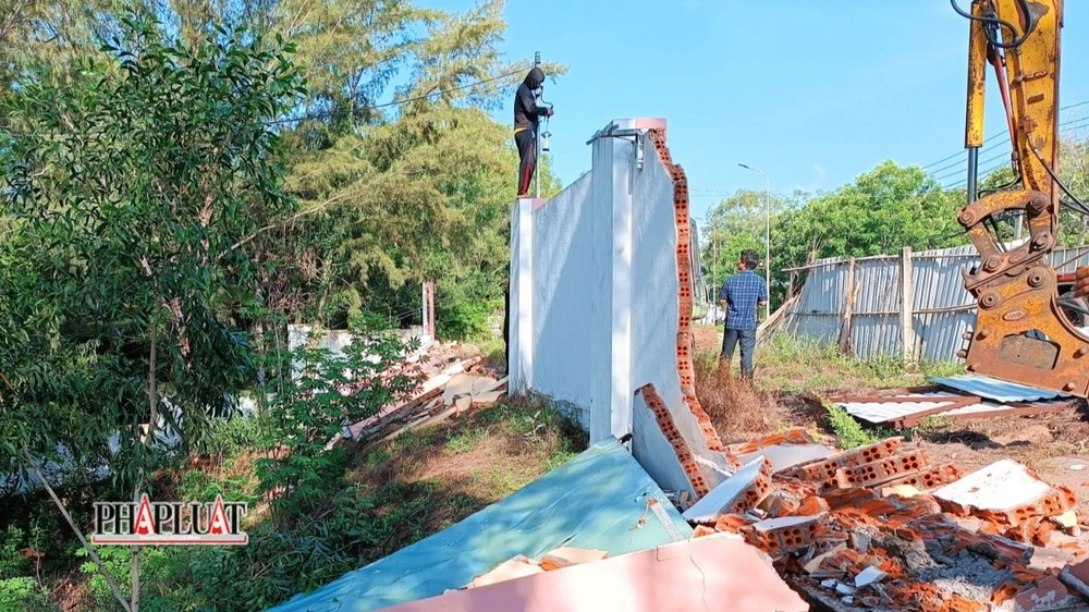Tháo dỡ phần hàng rào bằng tường gạch. Ảnh: NT