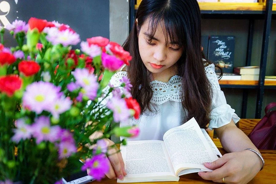 Tác giả bên không gian kệ sách nơi trọ của mình. Ảnh: NVCC