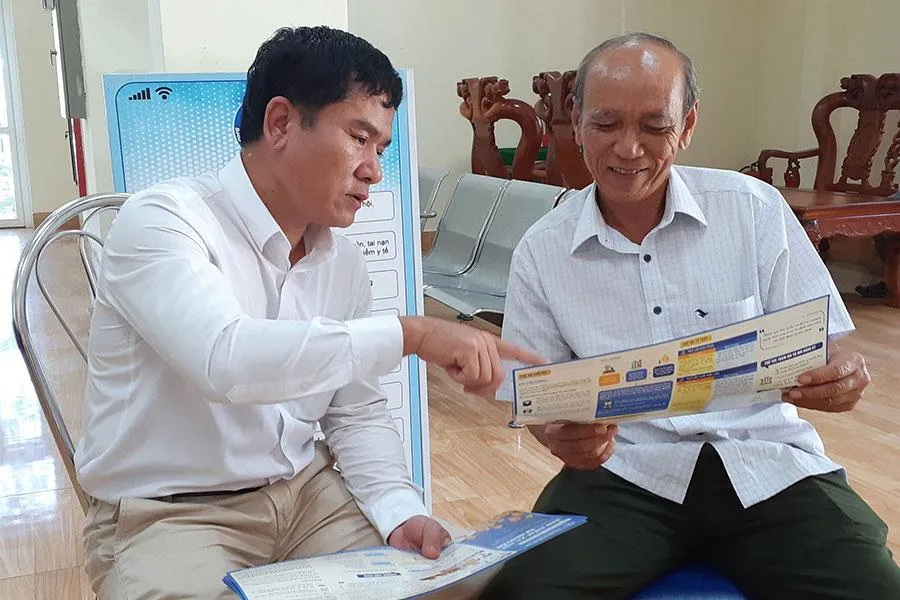 Ông Đoàn Văn Vinh (bên phải) đang được nhân viên BHXH huyện Lộc Ninh hướng dẫn về những quyền lợi khi tham gia BHXH tự nguyện. Ảnh: V.LONG