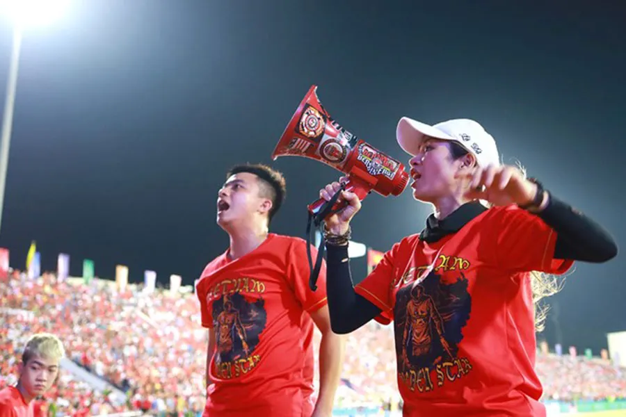 Hoàng Yến, Chủ tịch Hội Cổ động viên VGS, đang chỉ huy các cổ động viên cổ vũ cho đội tuyển Việt Nam.