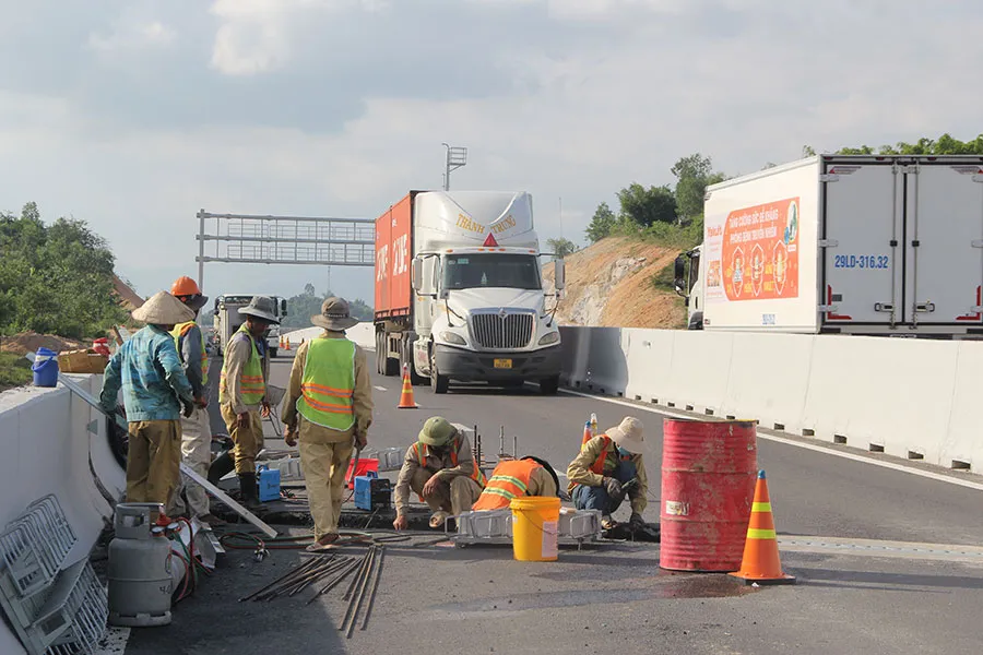 Các công nhân đang thi công trên cao tốc Nha Trang - Cam Lâm bên cạnh một làn xe vẫn lưu thông. (Ảnh chụp ngày 26-6) Ảnh: HUỲNH HẢI
