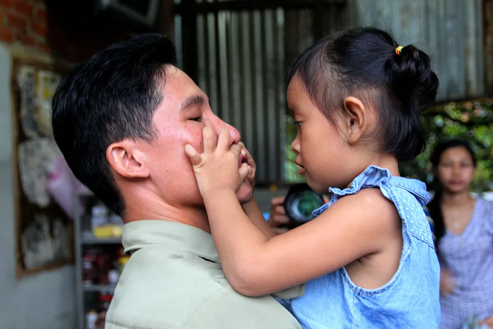 Bé Lan Anh ôm lấy cha nuôi Vũ Đình Khiên, dặn không được uống bia nhiều. Ảnh: HOÀNG GIANG