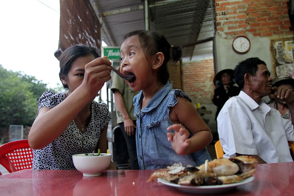 Bé Lan Anh về thăm nhà cũ được mẹ Nguyễn Thị Thu Trang chăm từng muỗng cơm. Ảnh: HOÀNG GIANG