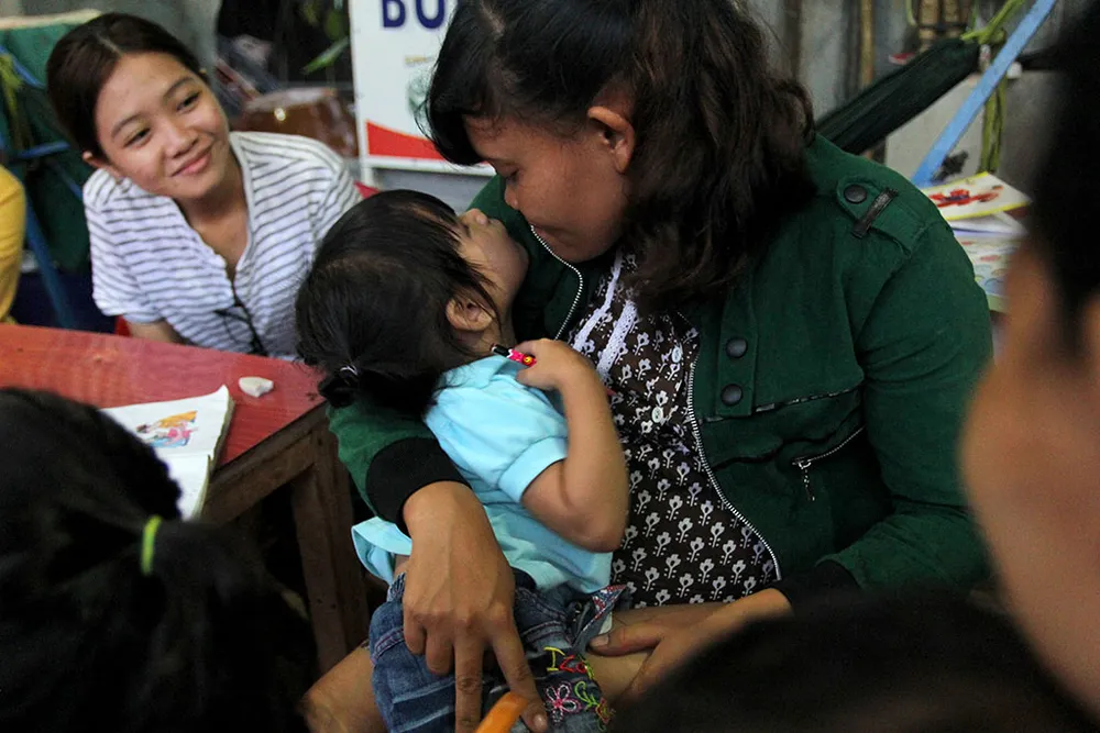 Mẹ nuôi Thị Liên và bé Ngọc Yến đùa giỡn với nhau trong buổi cơm tối. Ảnh: HOÀNG GIANG