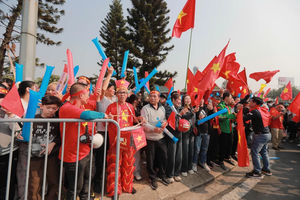 Các cổ động viên trong trang phục cờ đỏ sao vàng tại sân bay Nội Bài